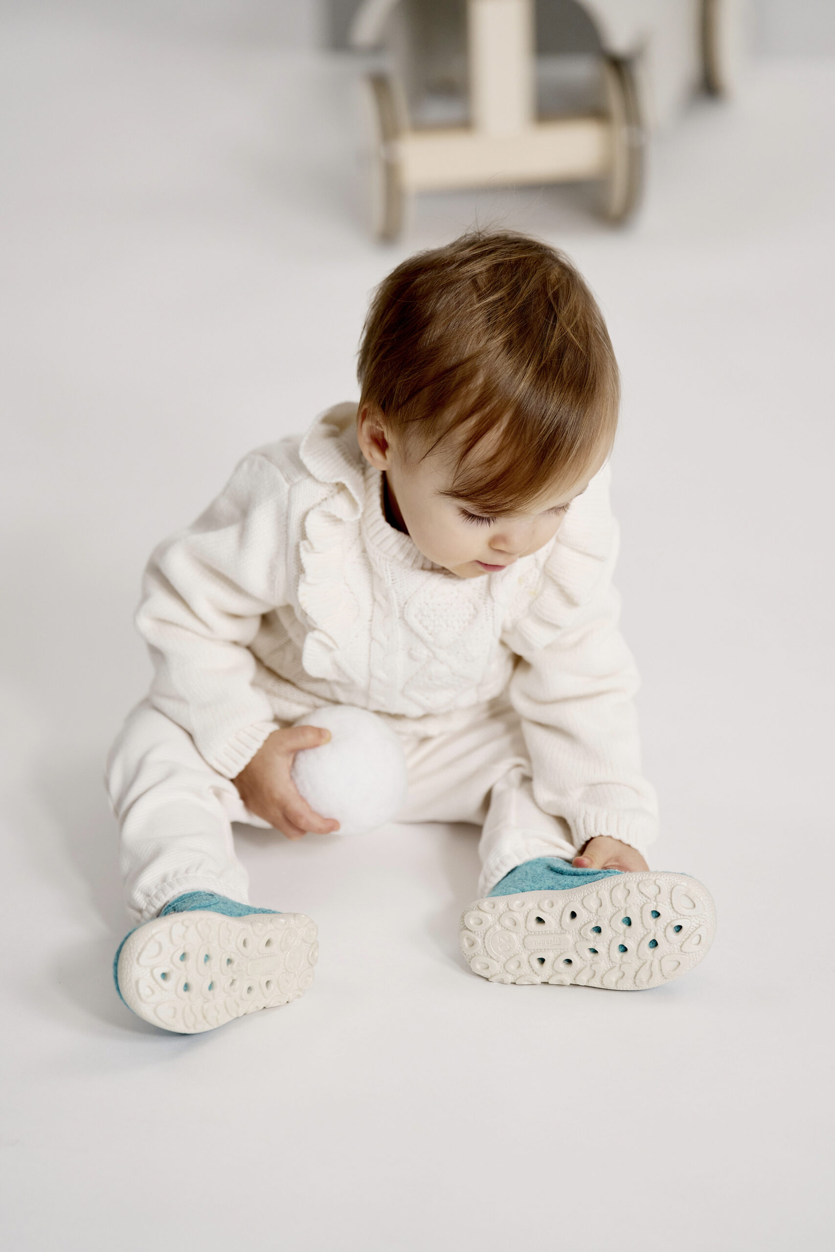 Kleinkind mit Lauflernschuhen sitzt am Boden